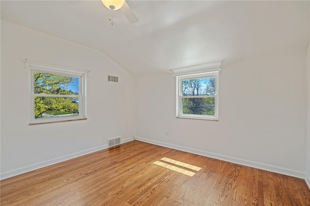 spare room with baseboards, visible vents, plenty of natural light, and vaulted ceiling