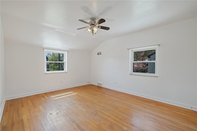 unfurnished room with ceiling fan, vaulted ceiling, visible vents, and light wood-type flooring