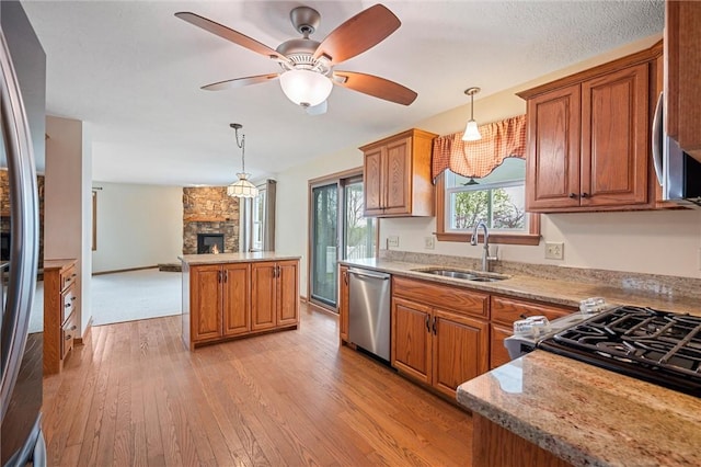 kitchen featuring brown cabinets, appliances with stainless steel finishes, a sink, and a fireplace