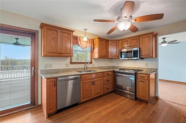 kitchen featuring a sink, appliances with stainless steel finishes, brown cabinets, and hardwood / wood-style floors