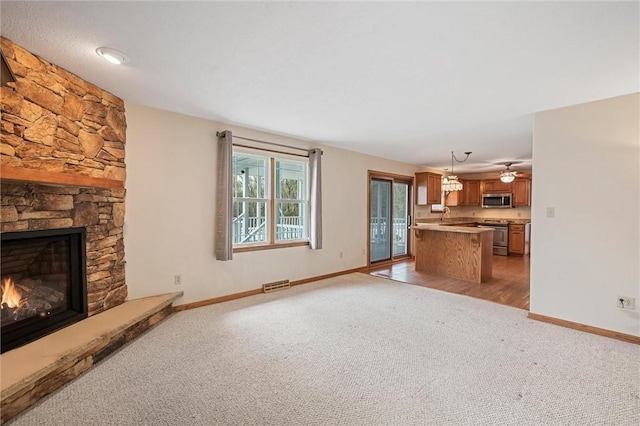 unfurnished living room featuring baseboards, light colored carpet, visible vents, and a fireplace