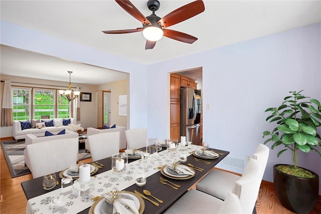 dining area with baseboards, light wood finished floors, and ceiling fan with notable chandelier