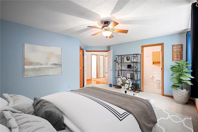 bedroom featuring a ceiling fan, a textured ceiling, baseboards, ensuite bathroom, and carpet