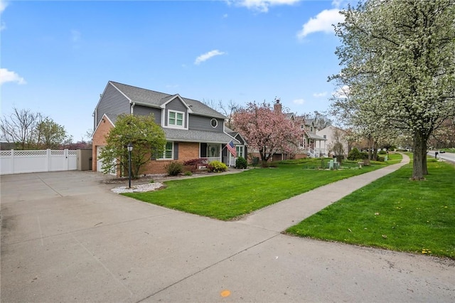 view of front of home featuring fence, a front yard, a chimney, brick siding, and driveway