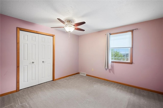 unfurnished bedroom featuring a ceiling fan, visible vents, baseboards, a closet, and carpet