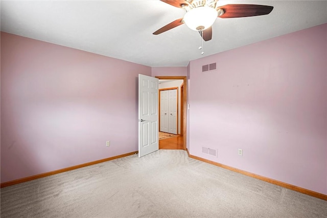 carpeted spare room featuring visible vents, a ceiling fan, and baseboards
