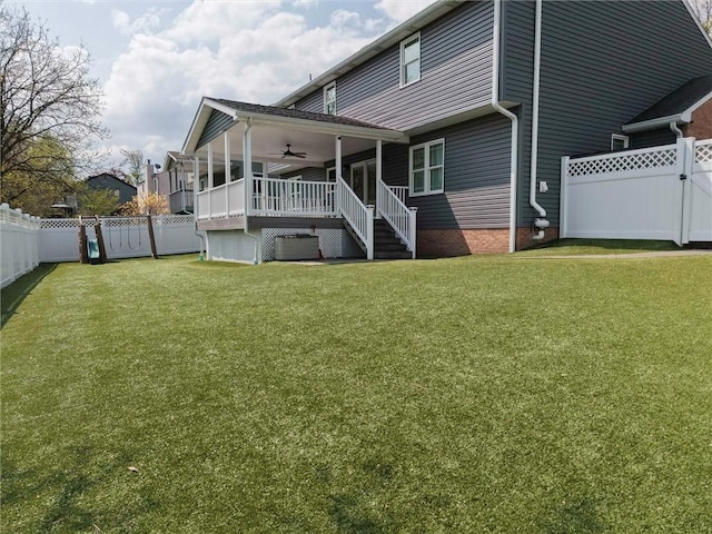 rear view of property with a ceiling fan, a lawn, a gate, stairway, and a fenced backyard