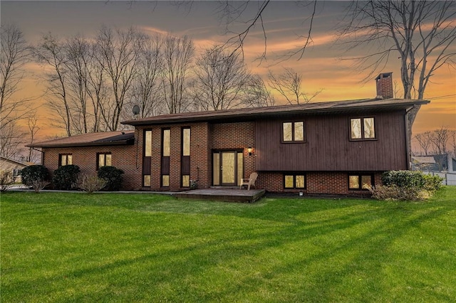 view of front of house with brick siding, a front lawn, and a chimney