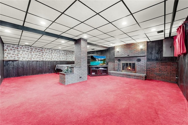 living area featuring wooden walls, carpet floors, a brick fireplace, a wainscoted wall, and decorative columns