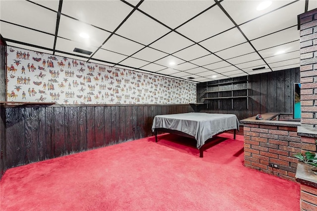 carpeted bedroom featuring wood walls, a wainscoted wall, wallpapered walls, a drop ceiling, and visible vents