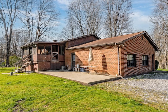 back of house featuring a lawn, a patio, stairway, and brick siding
