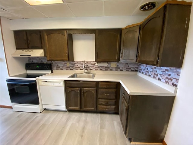 kitchen with electric range, white dishwasher, dark brown cabinets, a sink, and under cabinet range hood