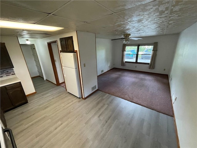 unfurnished room with baseboards, a ceiling fan, light wood-type flooring, and visible vents