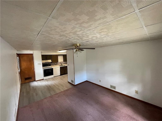 unfurnished living room with visible vents, a ceiling fan, baseboards, and a sink