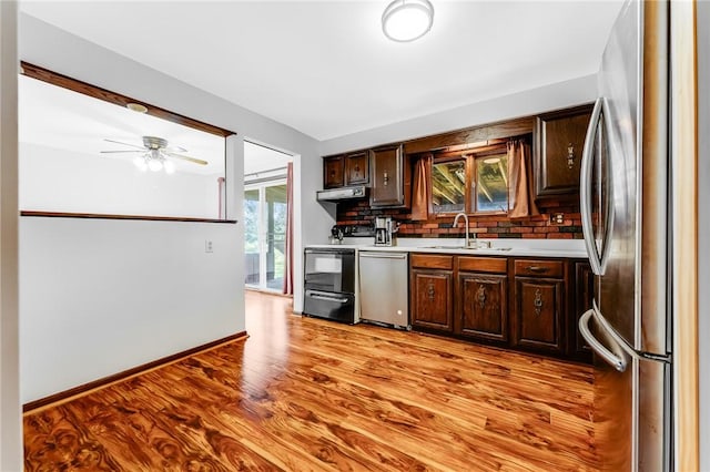 kitchen with dark brown cabinets, appliances with stainless steel finishes, a sink, light countertops, and under cabinet range hood