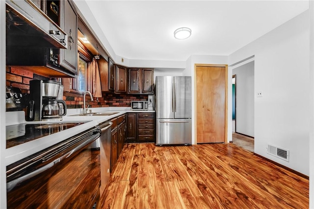 kitchen featuring dark brown cabinetry, appliances with stainless steel finishes, a sink, light countertops, and visible vents