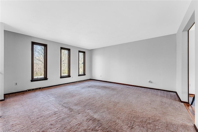 spare room with carpet flooring, baseboards, and visible vents