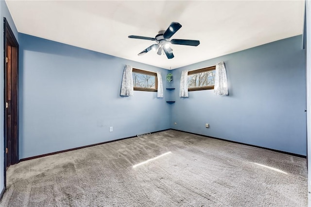 carpeted empty room featuring ceiling fan, visible vents, and baseboards
