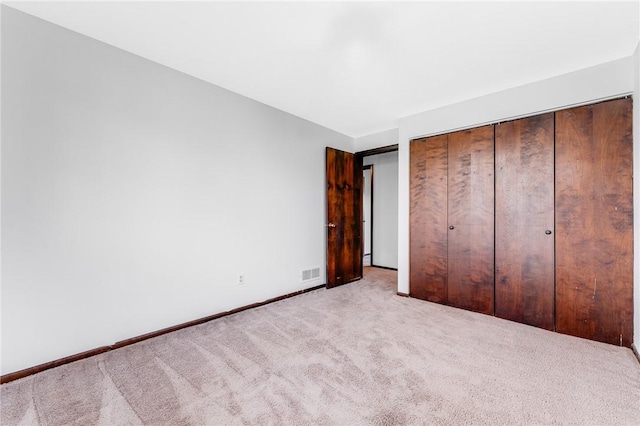 unfurnished bedroom with a closet, baseboards, carpet flooring, and visible vents