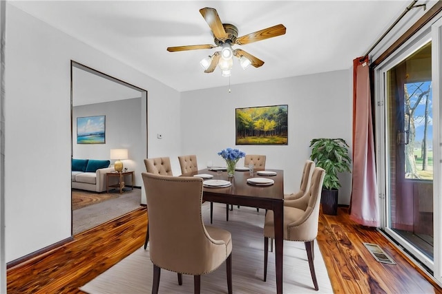 dining space with a ceiling fan, visible vents, and wood finished floors