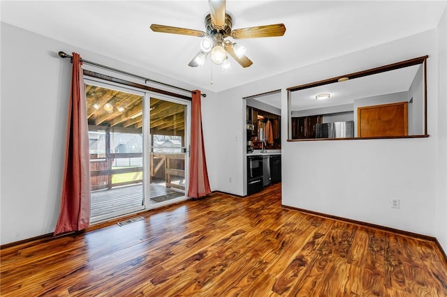 empty room featuring a sink, wood finished floors, and visible vents