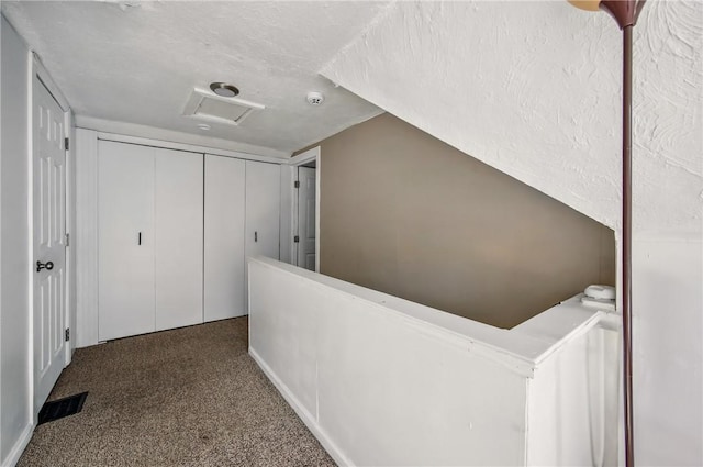 hall featuring carpet floors, attic access, and visible vents