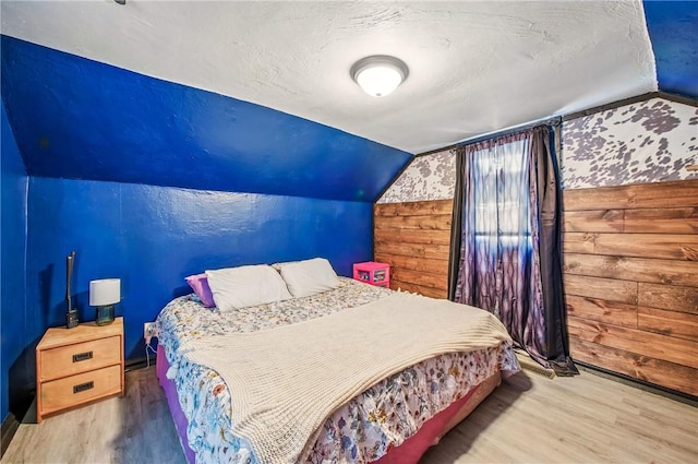 bedroom featuring wood finished floors and lofted ceiling