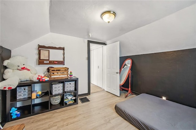 bedroom featuring wood finished floors and lofted ceiling