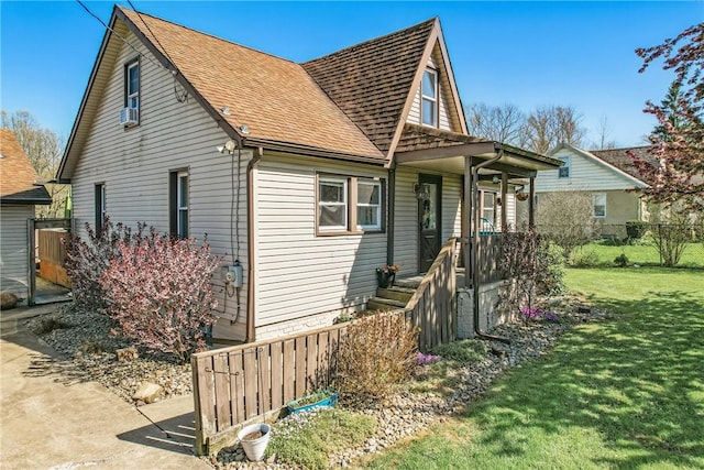view of front of house with roof with shingles, fence, and a front yard