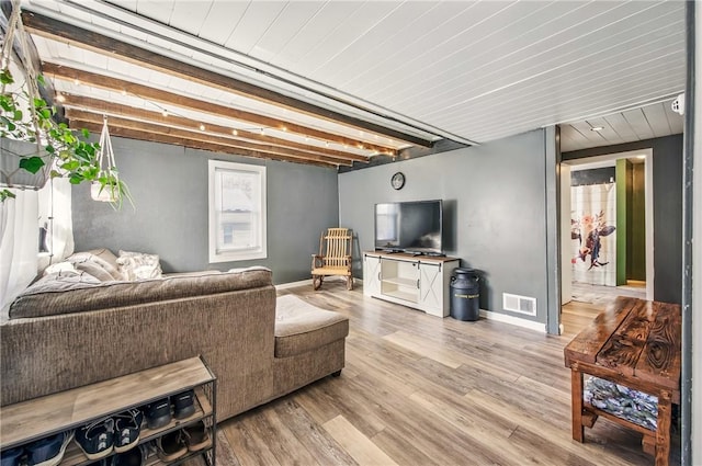 living room with baseboards, beamed ceiling, wood finished floors, and visible vents