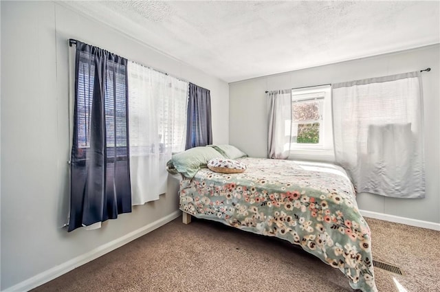 bedroom with baseboards, carpet, a textured ceiling, and visible vents