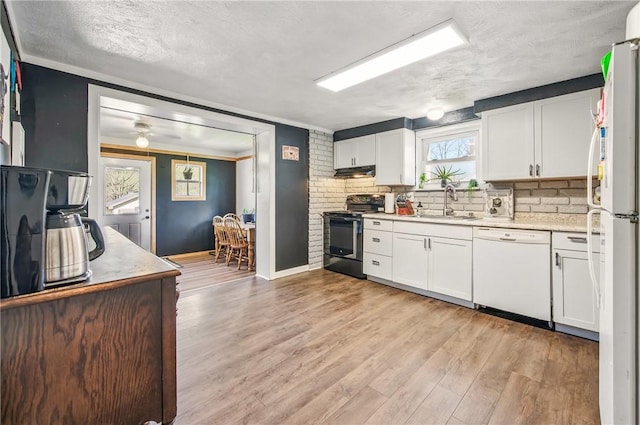 kitchen featuring white appliances, white cabinets, a sink, and light countertops