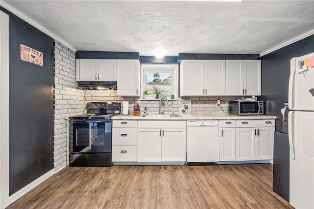 kitchen with wood finished floors, a sink, under cabinet range hood, and white appliances
