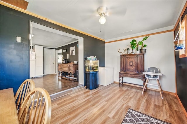 sitting room featuring crown molding, a ceiling fan, baseboards, and wood finished floors