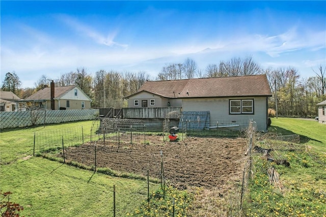 back of house with a lawn, fence, and a vegetable garden
