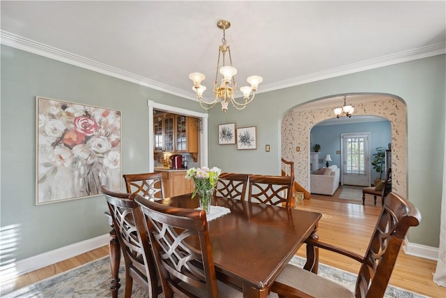 dining room with an inviting chandelier, arched walkways, and crown molding