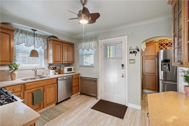 kitchen featuring radiator heating unit, light countertops, brown cabinets, a sink, and stainless steel appliances