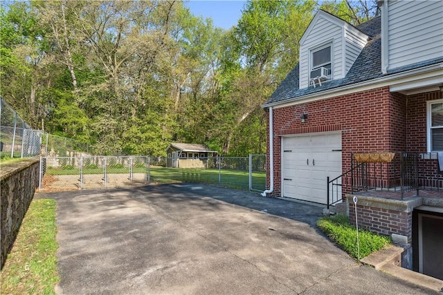 garage with fence, cooling unit, a gate, and aphalt driveway