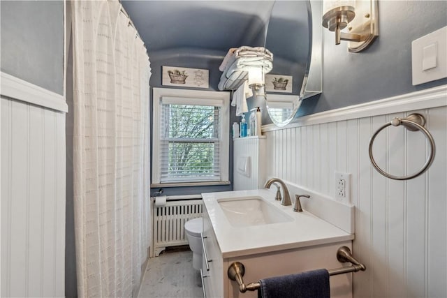 full bathroom featuring vanity, radiator, wainscoting, a decorative wall, and toilet
