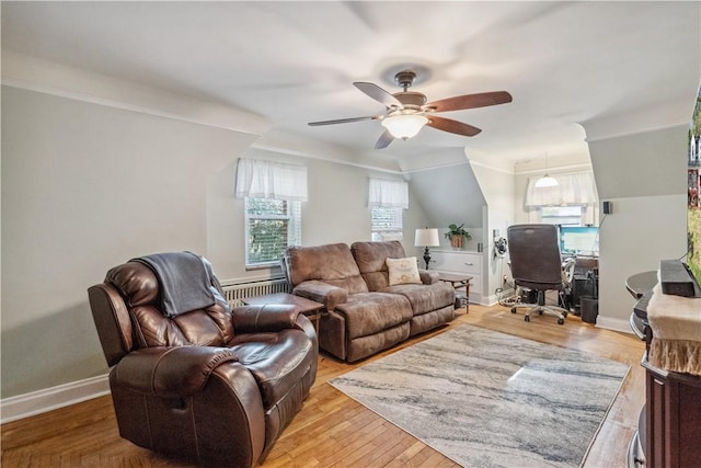 living area with a ceiling fan, baseboards, ornamental molding, and light wood-type flooring