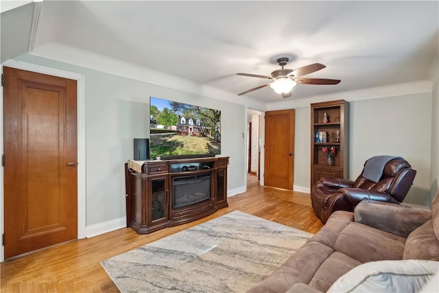 living area with ceiling fan, baseboards, and light wood-style floors