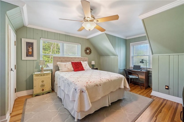 bedroom with light wood-style floors, ornamental molding, a decorative wall, and ceiling fan