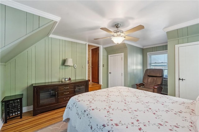 bedroom with crown molding, ceiling fan, a decorative wall, and wood finished floors