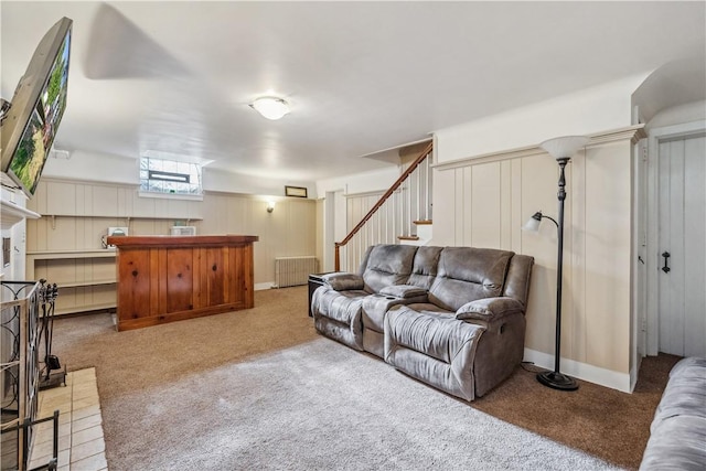 living area featuring carpet floors, radiator heating unit, and stairway