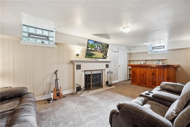 living room with carpet floors, a fireplace with flush hearth, a wainscoted wall, and a decorative wall