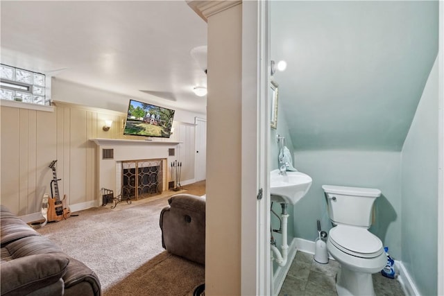 half bathroom with a fireplace with flush hearth, baseboards, toilet, and visible vents
