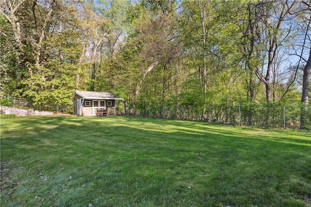 view of yard with a forest view, fence, an outbuilding, and a shed