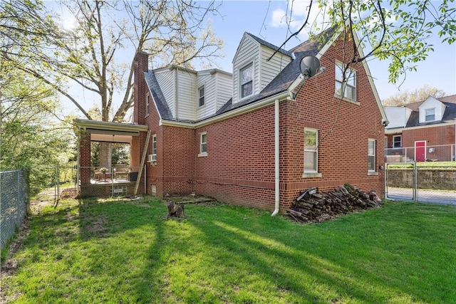 rear view of property featuring brick siding, fence, a yard, and a chimney