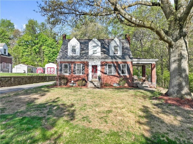 cape cod home featuring brick siding, a front yard, and a chimney