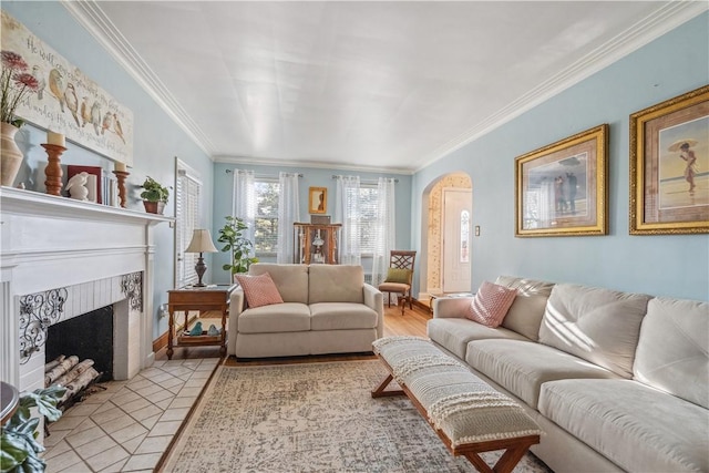 living area with crown molding, arched walkways, and a fireplace with flush hearth